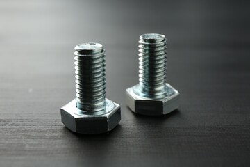 Metal bolts on dark wooden table, closeup
