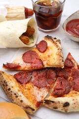 Different delicious fast food and soda drink on white marble table, closeup