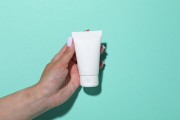 Woman with cosmetic product on turquoise background, closeup. Mockup for design