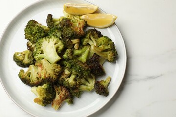 Tasty fried broccoli and lemon on white marble table, top view. Space for text