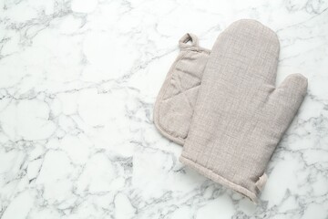 Oven glove and potholder on white marble table, flat lay. Space for text