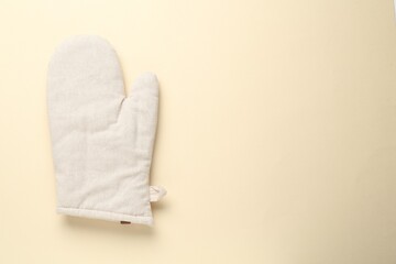 One oven glove on beige background, top view. Space for text
