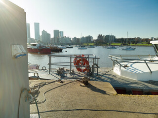 Electric charging station for boats, on a pier, with an urban landscape in the background.