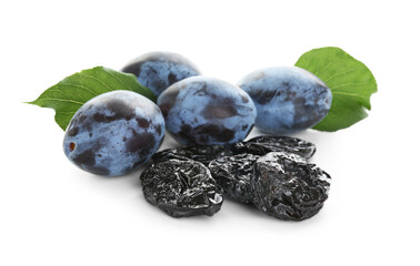 Dried prunes, fresh plums and green leaves isolated on white