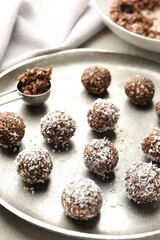 Tasty chocolate candies with nuts and coconut flakes on light table, closeup