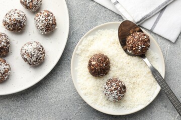 Making tasty chocolate candies with coconut flakes at grey table, flat lay