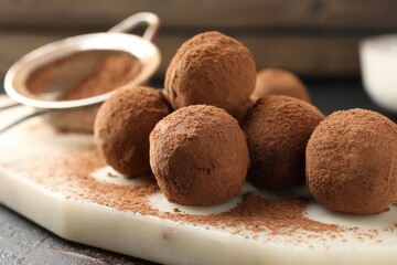 Tasty chocolate candies with cocoa powder on table, closeup