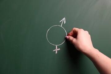 Sex Education. Woman drawing gender symbol on green chalkboard, closeup