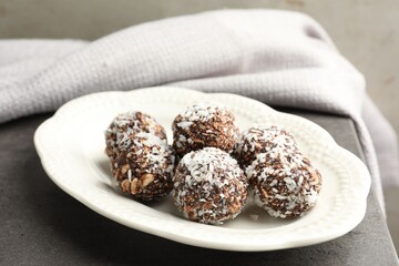 Tasty chocolate candies with nuts and coconut flakes on grey table, closeup