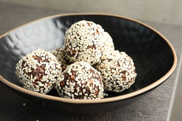 Tasty chocolate candies with nuts and sesame seeds on grey table, closeup