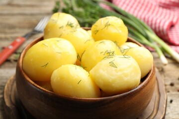 Tasty young boiled potatoes with dill served on wooden table, closeup