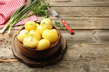 Tasty young boiled potatoes with dill on wooden table. Space for text