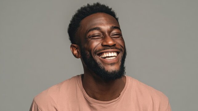 handsome unshaven young darkskinned male laughing out loud at funny meme he found on internet smiling broadly showing his white straight teeth positive human facial expressions and emotions no logos