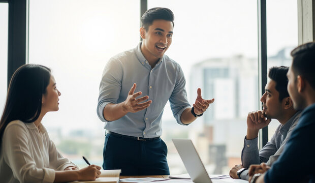 Young businessman confidently presenting ideas to colleagues in a modern office meeting room, engaging team members with open gestures and positive communication.
