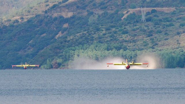 Two Italian seaplanes (CL-415) perform a water-collection maneuver at the B&aacute;rcena reservoir to help extinguish the forest fires in Galicia and El Bierzo
