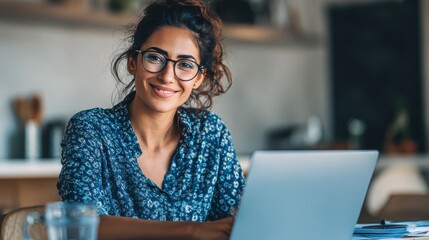 smiling indian young adult woman wearing glasses typing on laptop computer working at home office sitting at table happy female professional freelancer student studying online using notebook pc no lo