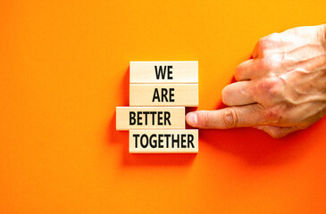 We are better together symbol. Concept words phrase We are better together on beautiful wooden blocks. Beautiful orange background. Businessman hand. Business We are better together concept Copy space
