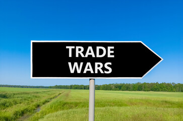 Trade wars symbol. Concept word Trade wars on beautiful black road sign. Beautiful green grass field blue sky background. Business trade wars concept. Copy space.