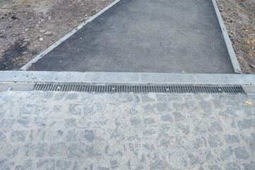 Fototapeta premium Overhead view of a transition between asphalt, stone pavement, and concrete curbing with a drainage channel. Concept for urban planning, road construction, and municipal infrastructure