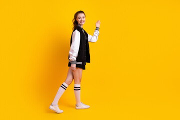 Cute woman in casual attire waving against a vibrant yellow background, representing positivity, youthfulness, and modern lifestyle
