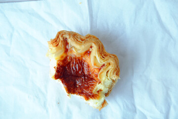 An overhead shot of a half-eaten Portuguese pastel de nata egg tart pastry on a clean, wrinkled white cloth