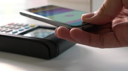 A person is using a phone to pay for something at a card reader