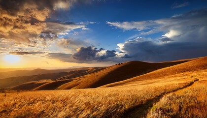 Obraz premium golden hillside under dramatic sunset sky with fluffy clouds