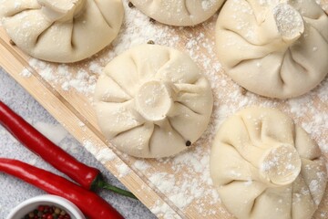 Uncooked khinkalis (dumplings) and spices on light grey table, flat lay