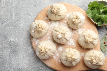 Uncooked khinkalis (dumplings) with ingredients on grey table, flat lay. Space for text