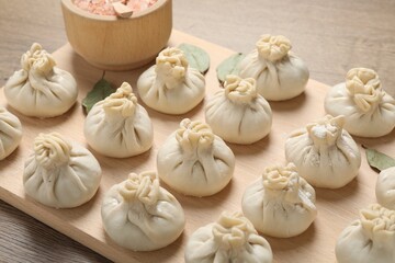 Uncooked khinkalis (dumplings) and spices on wooden table, closeup