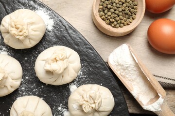 Uncooked khinkalis (dumplings), flour, spices and eggs on table, flat lay