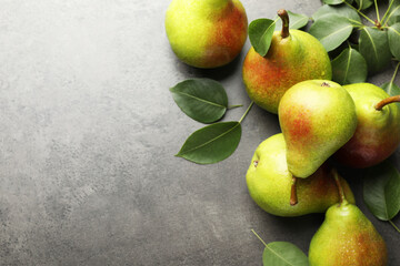 Fresh ripe pears and green leaves on grey table, flat lay. Space for text