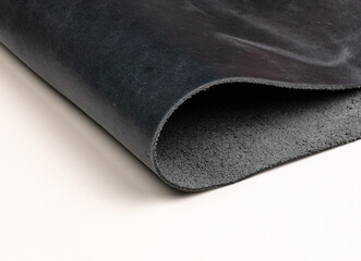 A gray leather material is rolled slightly, revealing its smooth texture and soft finish. The gentle curve highlights the versatility of the material, perfect for crafts or upholstery.