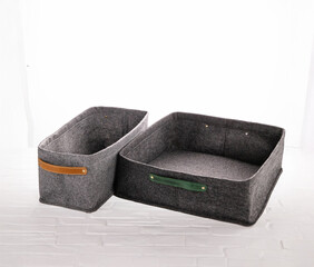 Two gray felt storage bins with leather handles are displayed. These bins provide a stylish and practical solution for organizing various items in any room, enhancing overall decor.