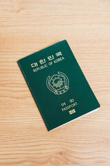 A passport of a nation sits on a plain wooden table, signifying travel and global identity.