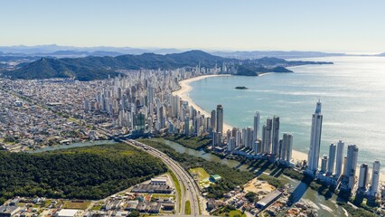 Aerial panoramic view of Balneário Camboriú with BR-101 highway and the Atlantic Ocean on a sunny day. © Marcio Eneas