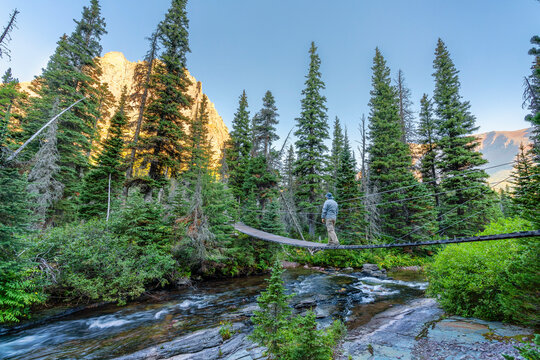 hikers crossing a swinging bridge in Glacier National Park