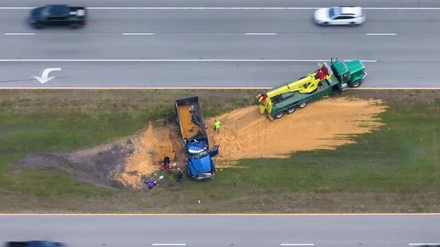 Wreckage of overturned transport truck surrounded by spilled agricultural load. Aerial scene of highway disruption.