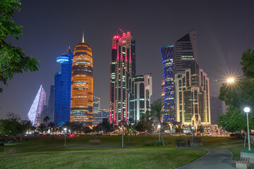 Doha city business downtown center panorama illuminated at night, with modern skyscrapers and sea in the foreground, Qatar