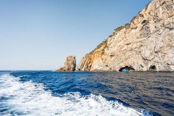 Naklejka premium Motorboat navigating near the rocky cap de creus natural park in catalonia, leaving a white foam trail on the deep blue mediterranean sea