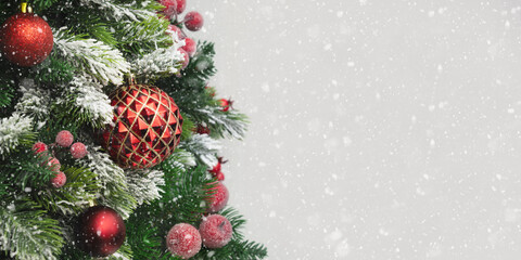 Christmas winter snowy banner with red balls and fir branches on white background. Xmas greeting card. Holiday time. Happy New Year. Space for text. Close up.