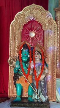 Colorful sculpture of hindu god shiv and goddess parvathi decorated with flowers and colourful lighting at temple. Religious concept.