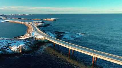aerial footage captures the iconic Atlantic Ocean Road Atlanterhavsveien in Norway, transformed by a pristine blanket of snow during winter.