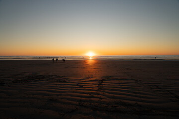 Wide sandy beach landscape with glowing sunset over the ocean