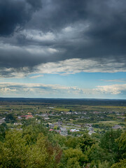Hilltop view of village under dramatic cloudy sky. Scenic panorama of countryside village before the rain