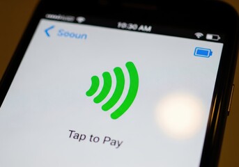 Smartphone held in hand showing contactless payment symbol clear bright light blurred background representing secure modern digital technology transaction innovation convenience