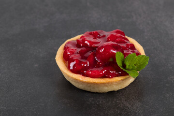 Cherry tartlet. With custard and mint. Dark gray background. Close up