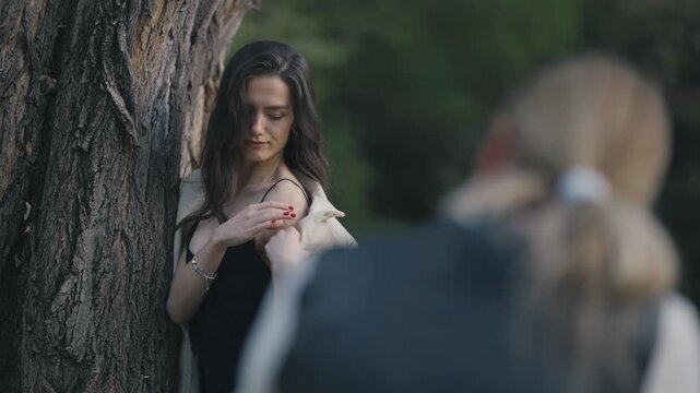 Professional photographer capturing a female model posing elegantly by a tree outdoors