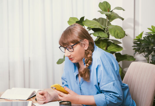 Serious elderly woman talking on smartphone in stylish modern flat - Powered by Adobe