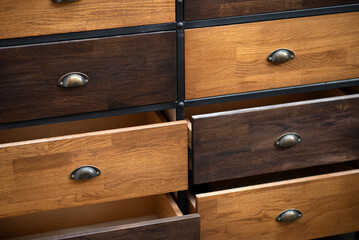 Close-up of wooden drawers with metal handles, some open and some closed, modern furniture design.